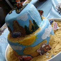 Cars Cake View 1 2 tier cars cake, sat over 24 hours before I got a good pic, so to me it looks droopy :( But all in all the kids loved it.