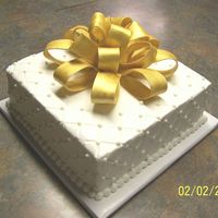 50Th Anniversary Gift Cake Cake is covered with buttercream. Bow is made from gumpaste/fondant and painted with gold luster dust. The pearls were made from fondant.