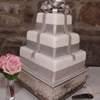 Wedding Cake Varied flavors per tier, fondant covered, gumpaste bow and bands.