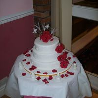 Round Wedding Cake With Ruby Roses A three tier round cake with royal icing hearts on, some of the hearts have small diamonte placed in. The Roses were made with flowerpaste...