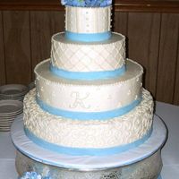 White With Blue Ribbon White buttercream with blue fondant ribbon featuring a variety of patterns on each tier, including a monogram. Silk hydrangeas on top and...