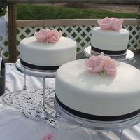 First Wedding Cake Chocolate w/raspberry filling. Covered in MMF with gumpaste fantasy flowers. Black and pink ribbon around border. Brides colors were black...