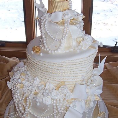 White & Gold Whimsical Cake Accented With Pearls, Bows, And Wedding Rings....