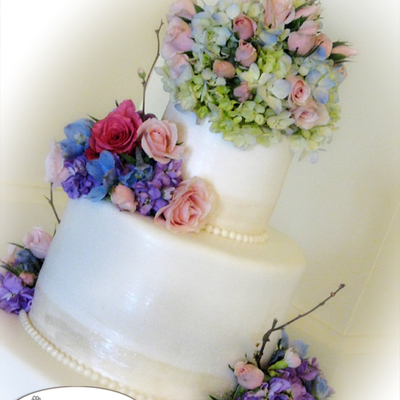Wedding Cake With Satiny Pearlized Border And Fresh Flowers.