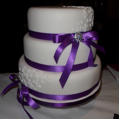 Three Tier Round Wedding Cake With Purple Ribbon And Brooch Detail