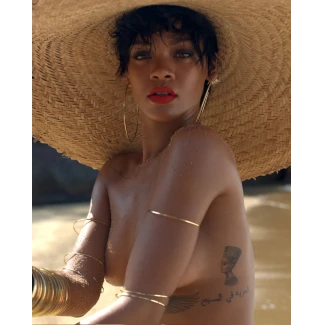 Enchanting beauty Rihanna hides her big boobs and posing topless with a large hat