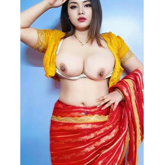 Beauty with large pale melons and dark erect nipples stands nude in sheer yellow blouse while red and gold sari covers lower body against light blue wall