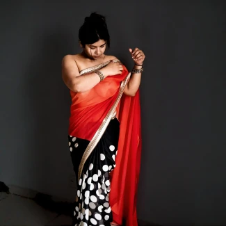 Desi woman in a braless thin red saree with black polka dots, exposed right shoulder, showing her naked boobs clearly