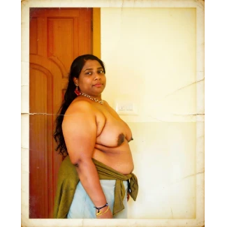 Desi MILF with large pendulous tits wearing pearl necklace and red ornate earrings against wooden door