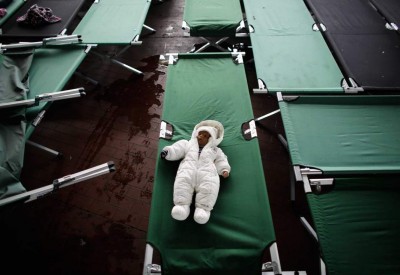 Three month old baby Parwan from Afghanistan sleeps on a bed at the temporary registration center of the southern German border town Passau, Tuesday, Sept. 15, 2015. Refugees were taken to the center from trains, cars or were picked up on streets.  (AP Photo/Markus Schreiber)