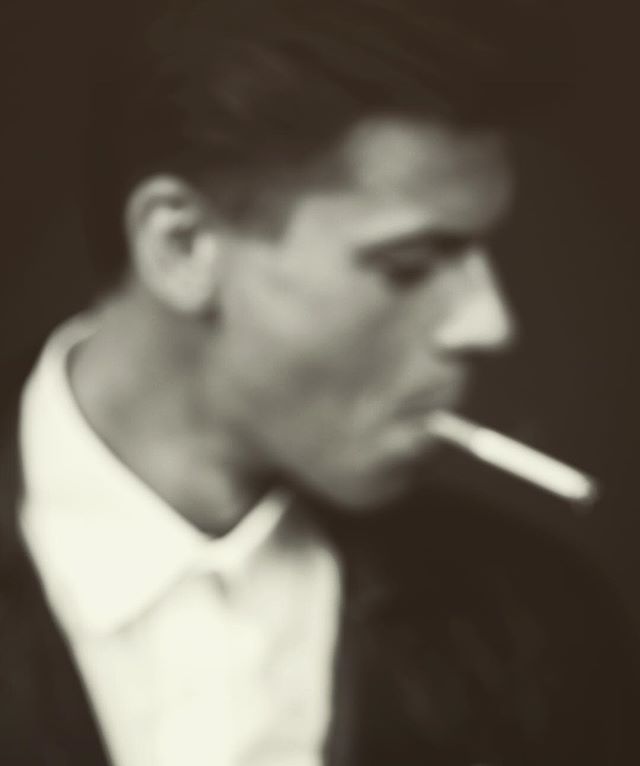 A blurred, vintage style portrait of a man smoking, with a contemplative and moody atmosphere.