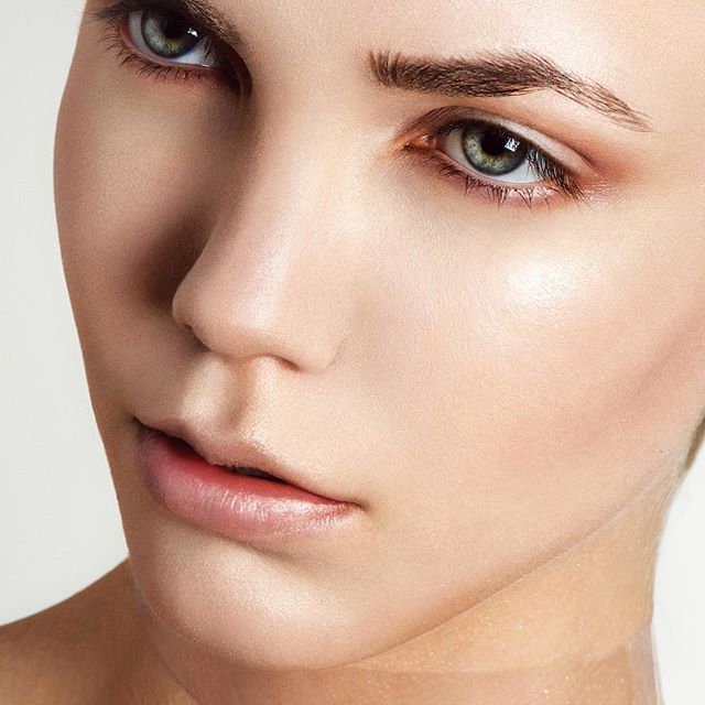 Close-up portrait of a woman with clean, natural makeup and soft lighting.