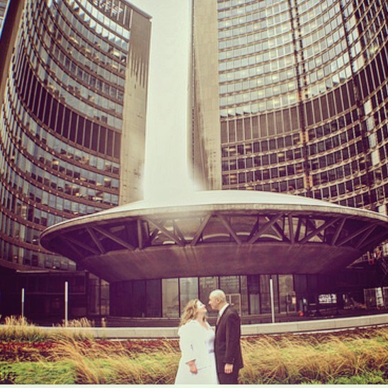 A newlywed couple shares a romantic moment in front of Toronto City Hall on their wedding day.
