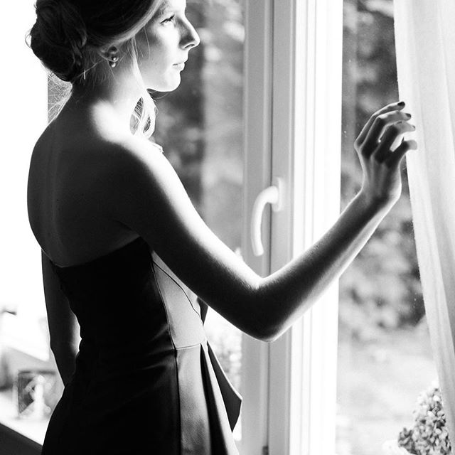 A woman in an elegant dress gazes out the window, lost in thought.