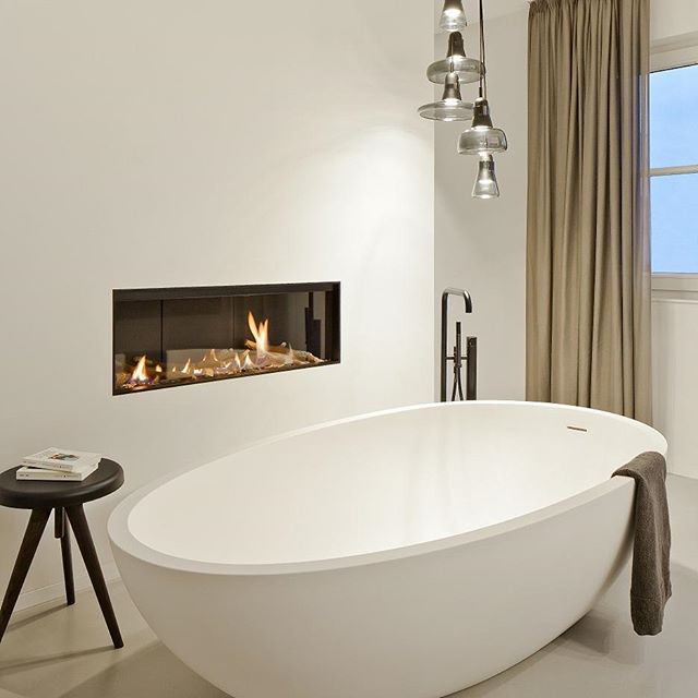 A modern bathroom featuring a freestanding tub, fireplace, and warm lighting, creating a serene and relaxing spa-like atmosphere.