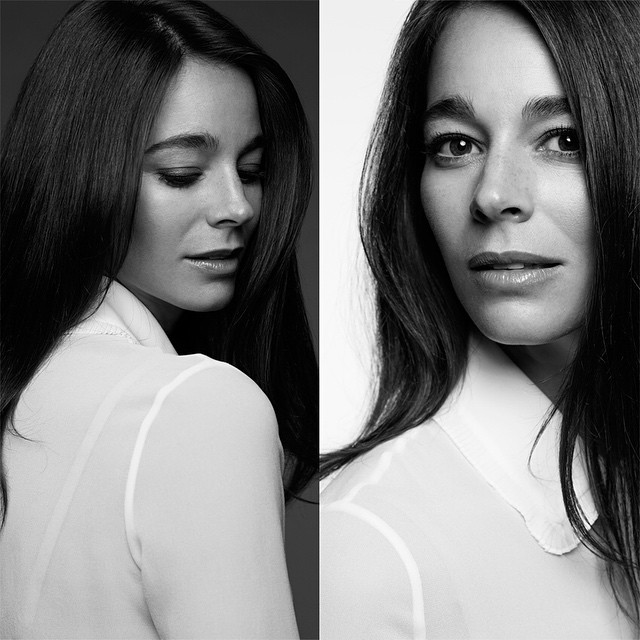 A black and white portrait of a woman in a white shirt with a calm and confident expression.