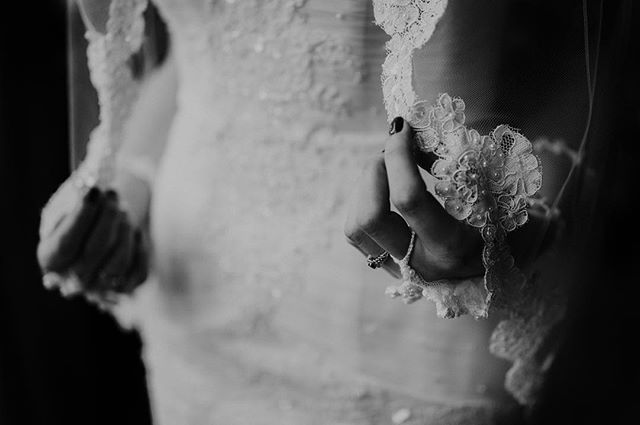 A bride holds her lace veil, showcasing a classic and elegant wedding style. Bridal fashion editorial.
