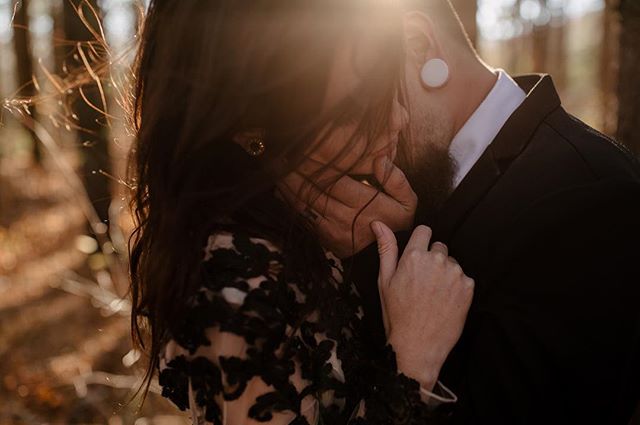 An embracing couple shares an intimate moment in a sun-drenched forest setting, radiating love and connection.