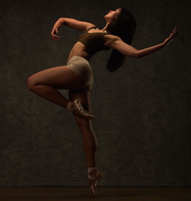 A female ballerina strikes a pose, showcasing strength and grace through the art of dance in a studio setting.