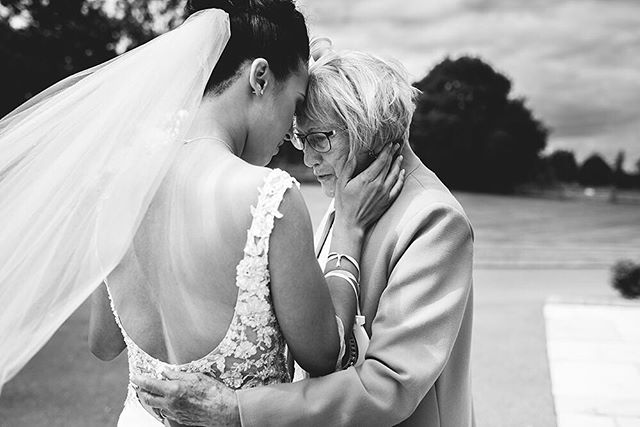 A bride shares an intimate moment with her grandmother at a wedding, showcasing a tender generational bond in black and white.