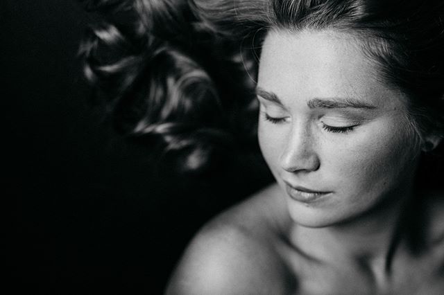 A serene black and white portrait of a woman with her eyes closed.