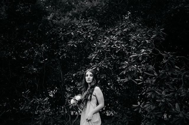 A woman in a dress holding a bouquet stands in a garden, creating a dreamy, vintage atmosphere.