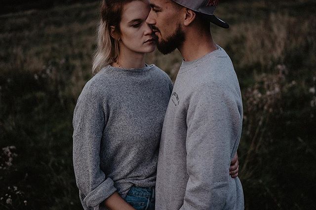 A loving couple embraces outdoors in a field, creating an intimate and tender moment.