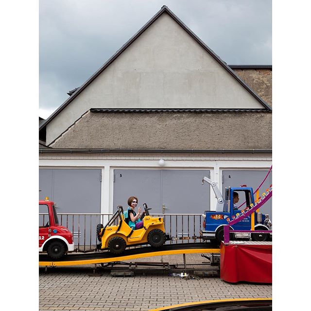 A child is enjoying an amusement ride with colorful vehicles on a track outdoors, exuding fun and excitement.