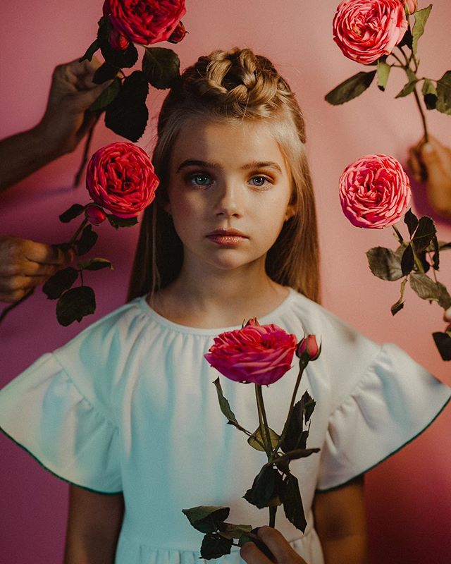 A girl with braided hair poses with roses, creating a dreamy and intimate portrait for advertising or editorial use.