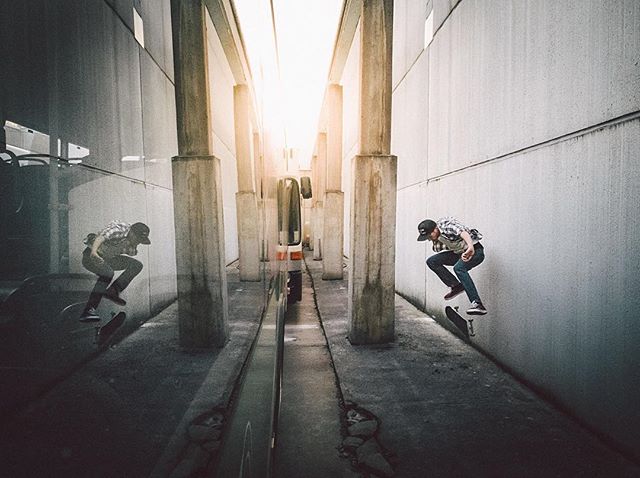 A skateboarder performs a trick in an urban alleyway, captured in a dynamic and energetic shot with a reflection.