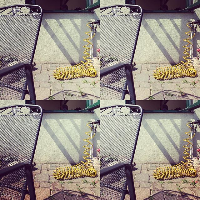Outdoor patio with a garden chair and a yellow hose, sunny day.