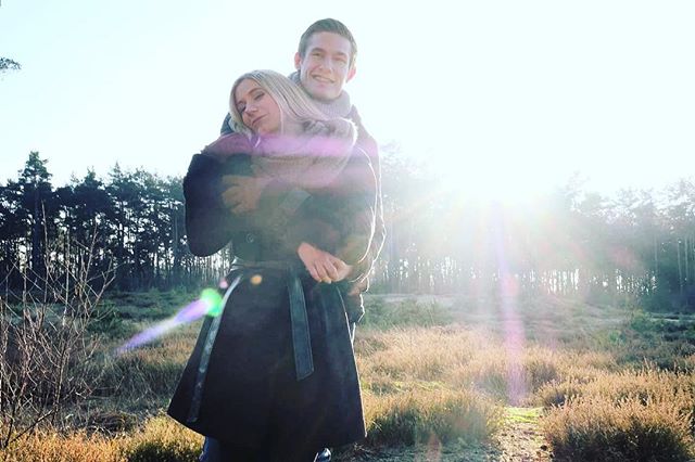 A couple embraces in a sunlit field, radiating warmth and affection in a serene outdoor setting.