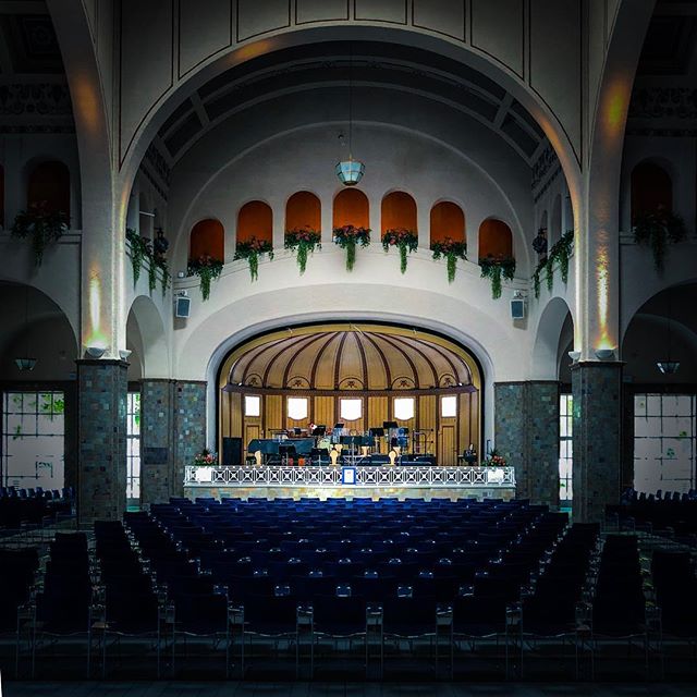 A beautifully designed auditorium with a stage and rows of blue seats, ready for a performance.