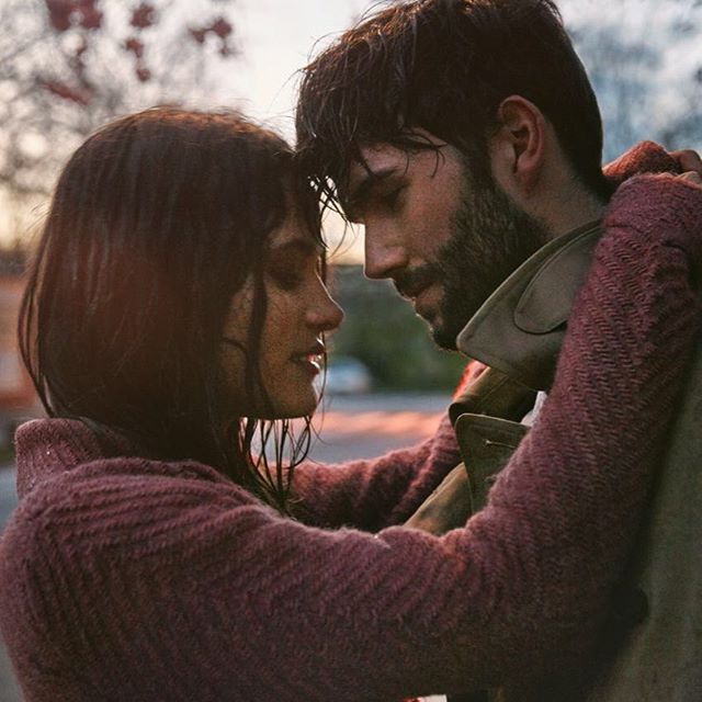 A couple embraces tenderly outdoors, creating a warm and intimate moment.