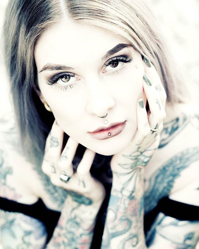 A tattooed woman with piercings poses for a striking close-up, showcasing unique style.