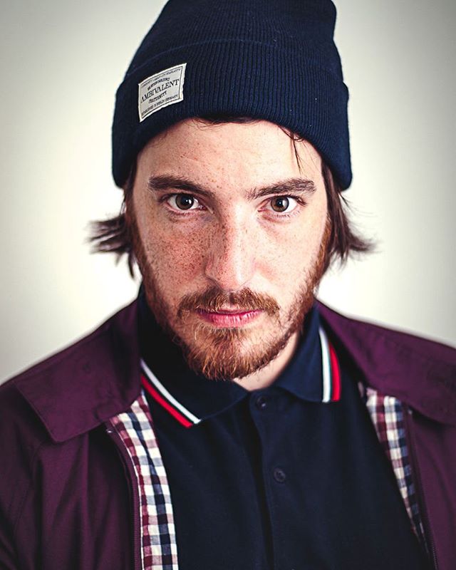A portrait of a bearded man wearing a beanie hat and jacket.
