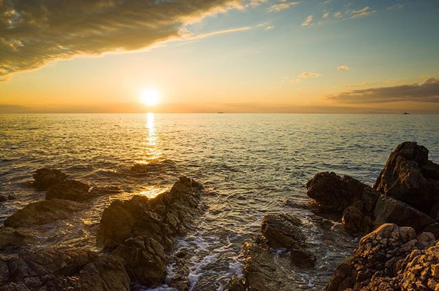 Golden sunset over the ocean featuring rocky coastline, creating a tranquil and scenic seascape perfect for travel and relaxation themes.