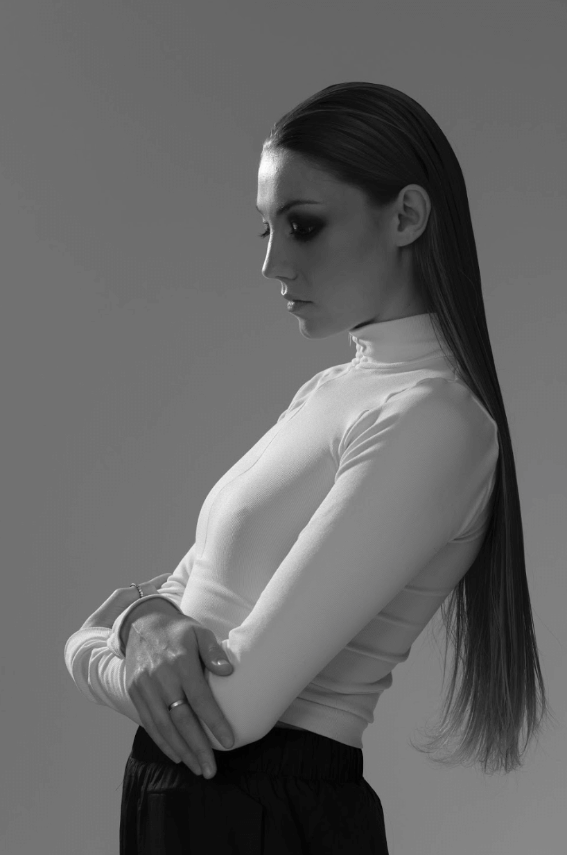 A woman poses in a studio with clean light for a modern, minimalist fashion editorial.