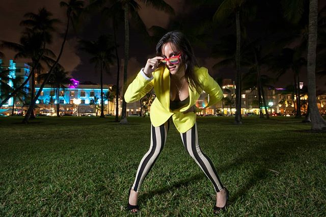 A woman in a yellow blazer poses at night, blending fun and style in an urban setting.