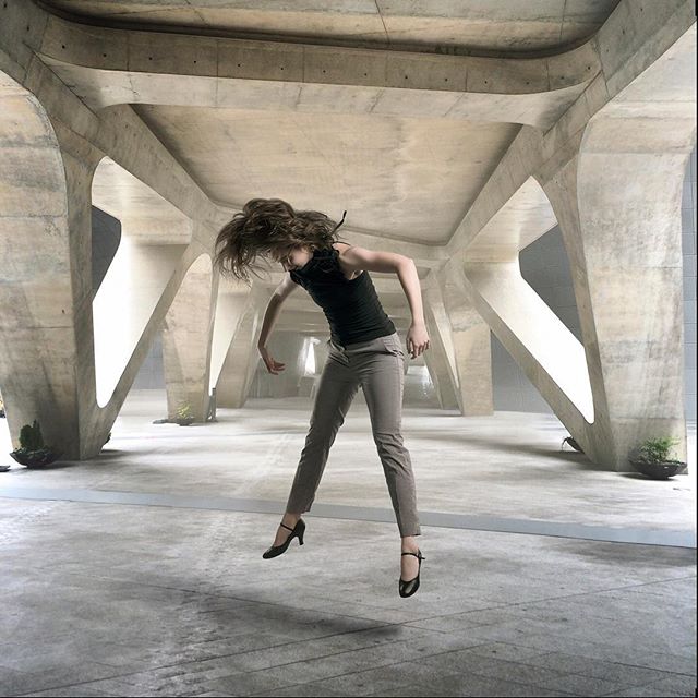 A woman leaps in a concrete structure, capturing dynamic movement and urban artistry in a single frame.