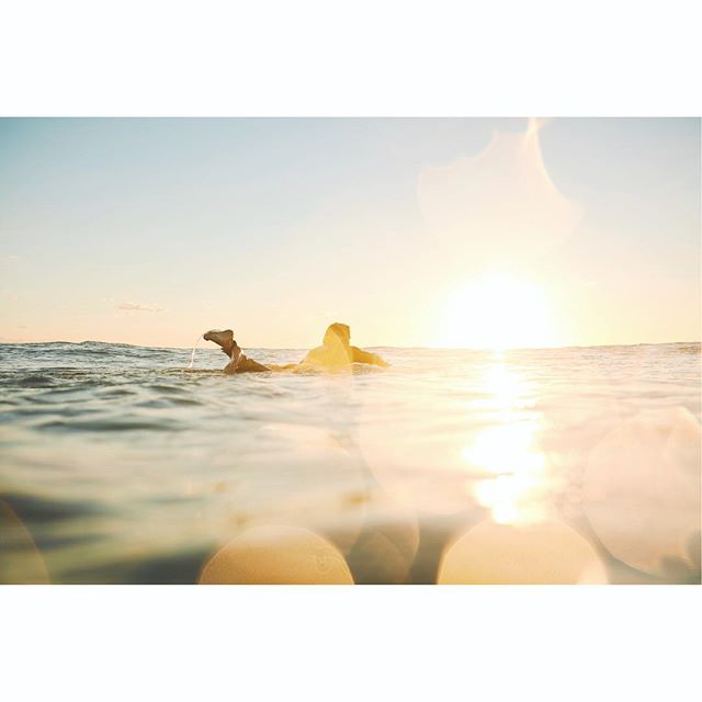 A surfer enjoys a tranquil moment at sea during sunset.