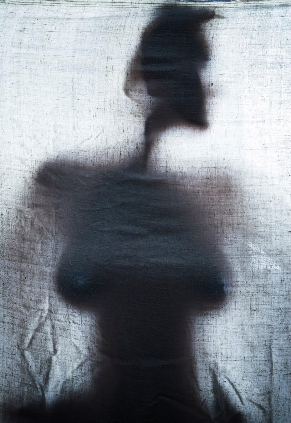 A silhouette of a woman's body is seen through a translucent fabric, creating an artistic and mysterious effect.