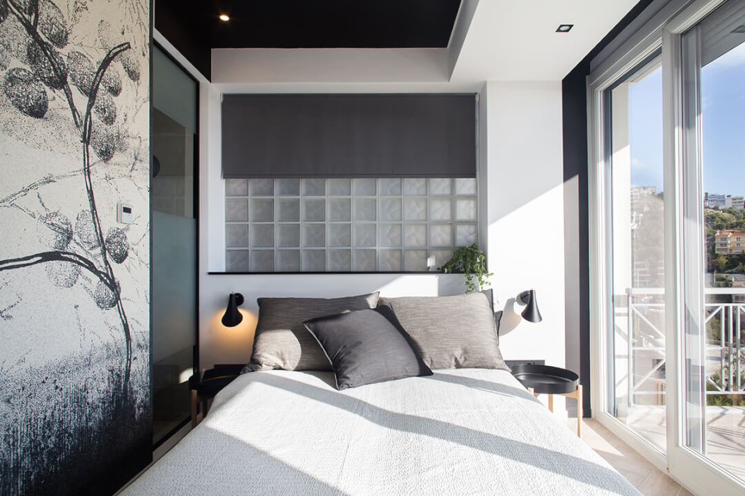 A modern bedroom features a cozy bed, window, and balcony for a calm and relaxing atmosphere.