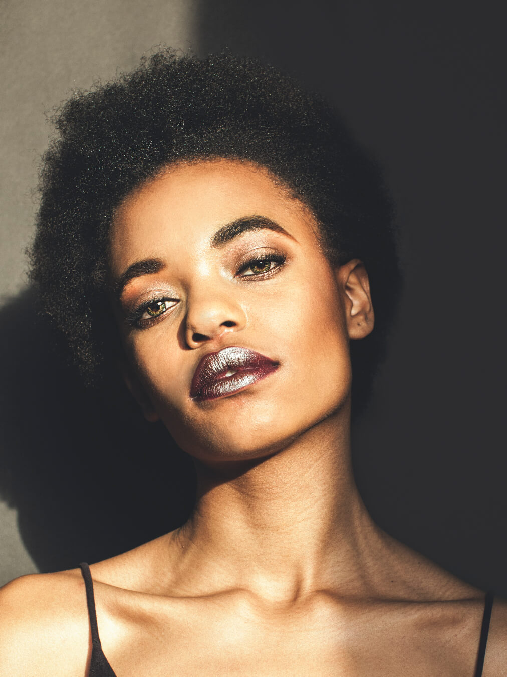 Portrait of a young woman with bold makeup in a studio setting, showcasing her beauty and confidence.