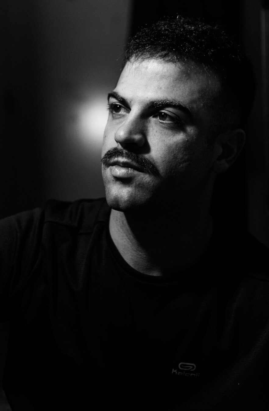 A serious man with a mustache looks off-camera in a high-contrast black and white portrait.
