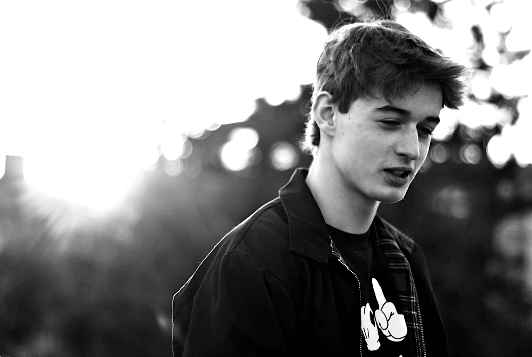 A moody black and white portrait of a teenage boy with shallow depth of field.