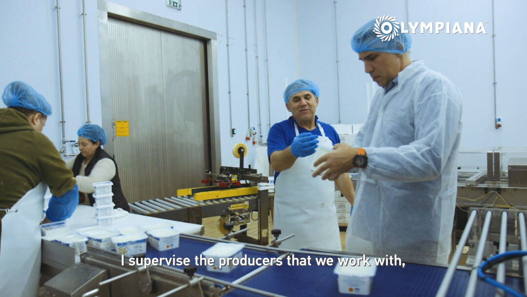Workers package dairy products on a production line inside a bright factory.