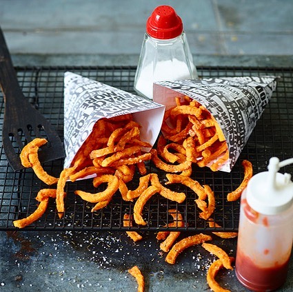 Crispy sweet potato fries in paper cones with salt and ketchup, perfect for a quick snack or side dish.