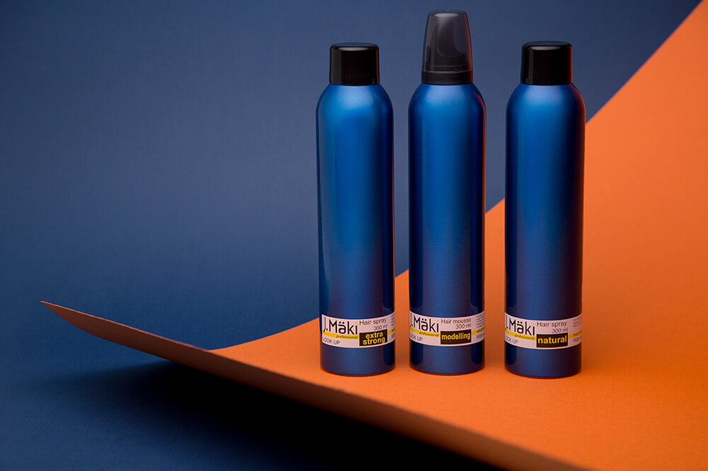 Three blue Maki hair spray and mousse bottles on a modern blue and orange background for beauty and product promotions.