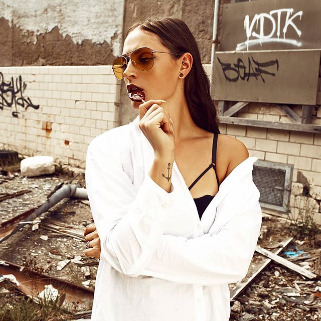 A woman with sunglasses enjoys a lollipop in an urban setting. This eye-catching image can enhance your brand image.